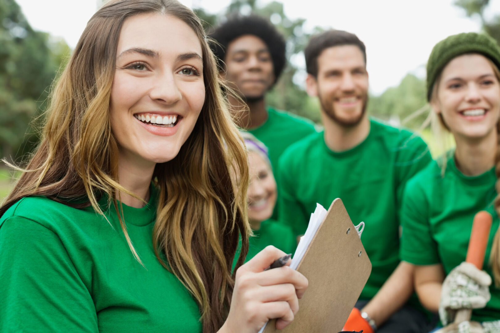 Happy beautiful environmentalist holding clipboard with voluntee Happy beautiful environmentalist holding clipboard with voluntee