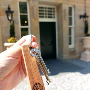 Boleskine House wooden keyring in a hand in front of door